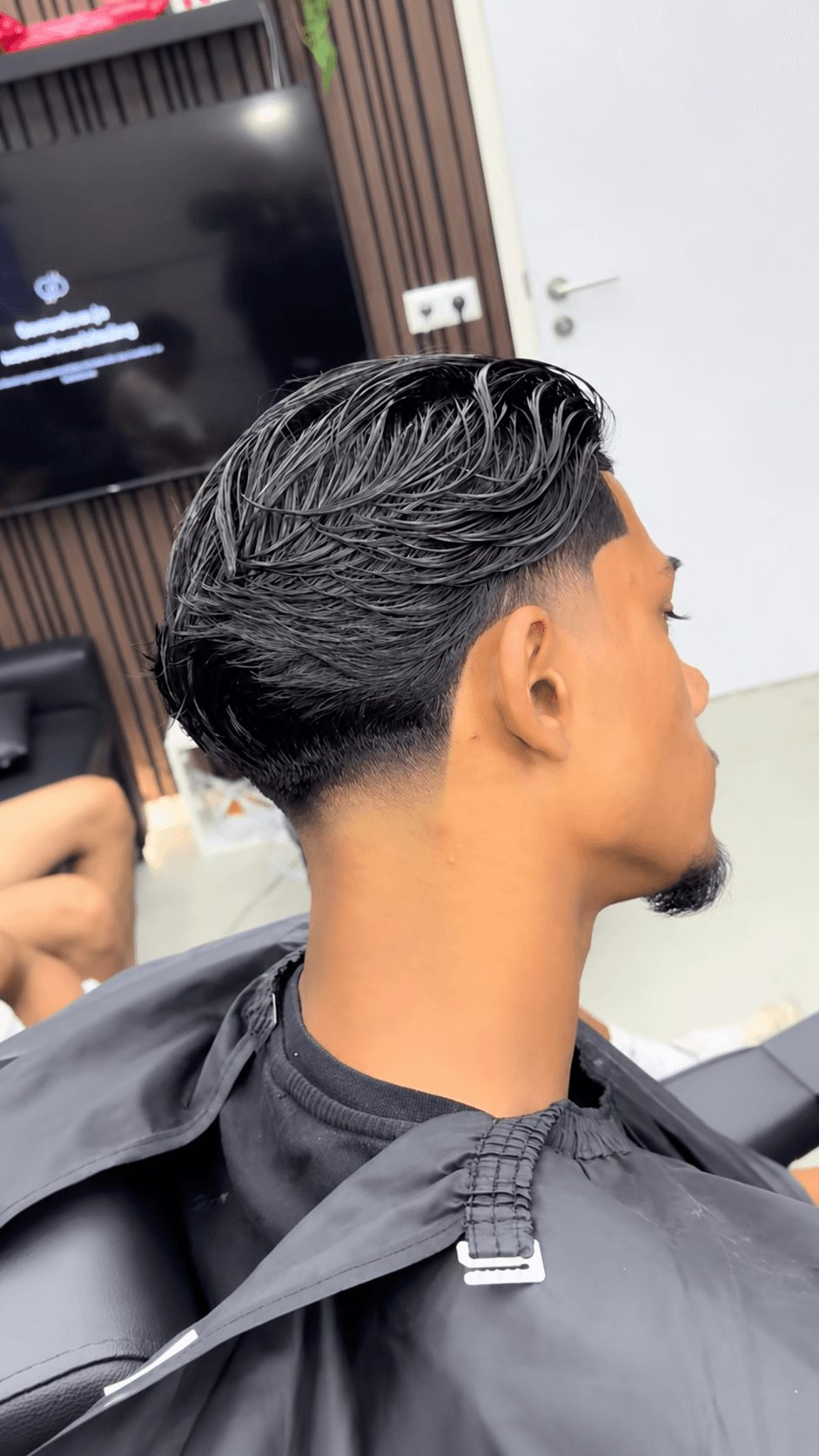 Zijprofiel van nat achterover gestyled haar met een low taper