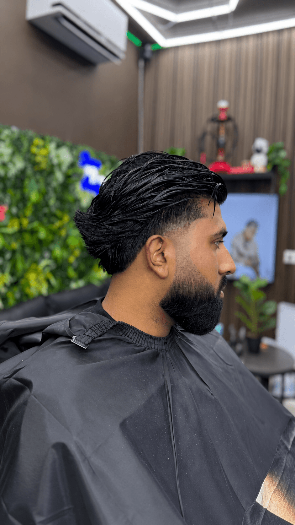 Zijprofiel van nat achterover gestyled haar met een taper fade en volle baard
